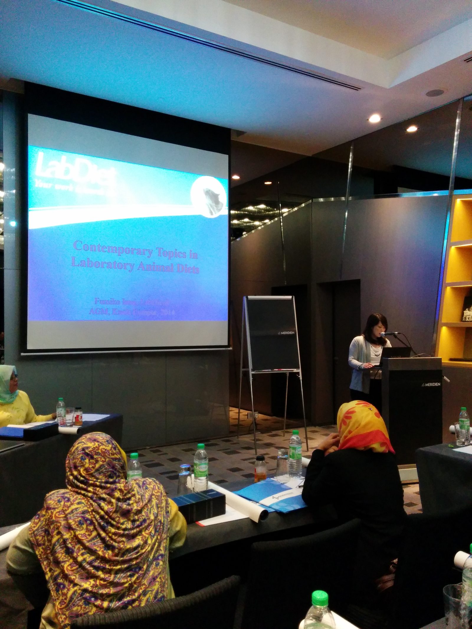 A speaker at the lectern beside a slide titled Contemporary Topics in Laboratory Animal Diets