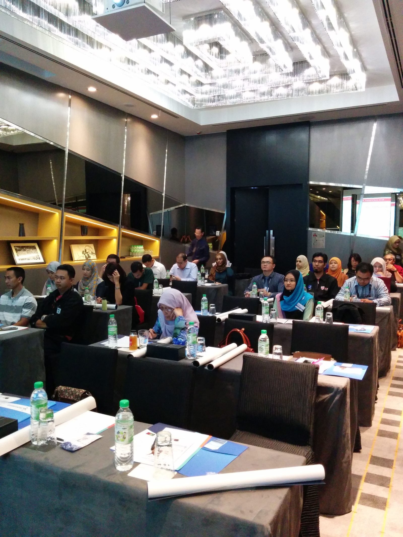 Participants seated at rows of tables in the seminar room, facing the front