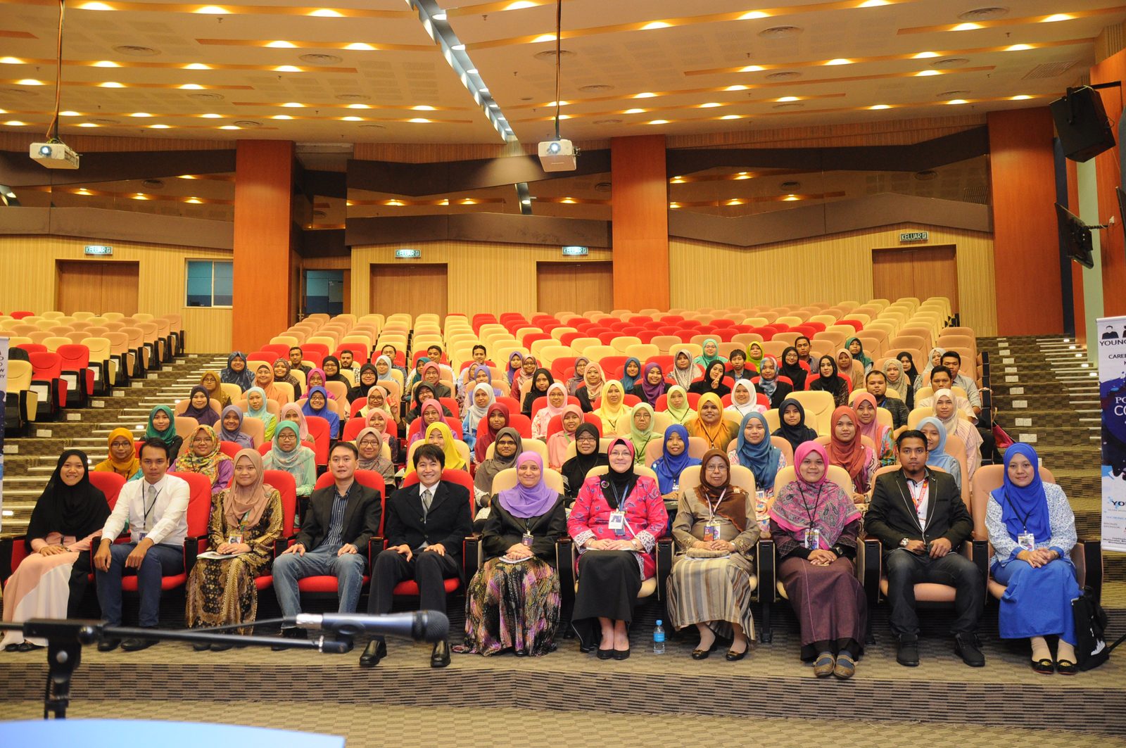 A large group of participants seated in rows for a group photo in the Main Auditorium at UiTM Sungai Buloh.