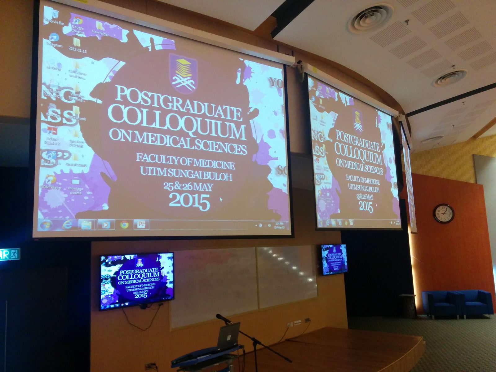 Auditorium screens showing the title slide of the Postgraduate Colloquium on Medical Sciences 2015.