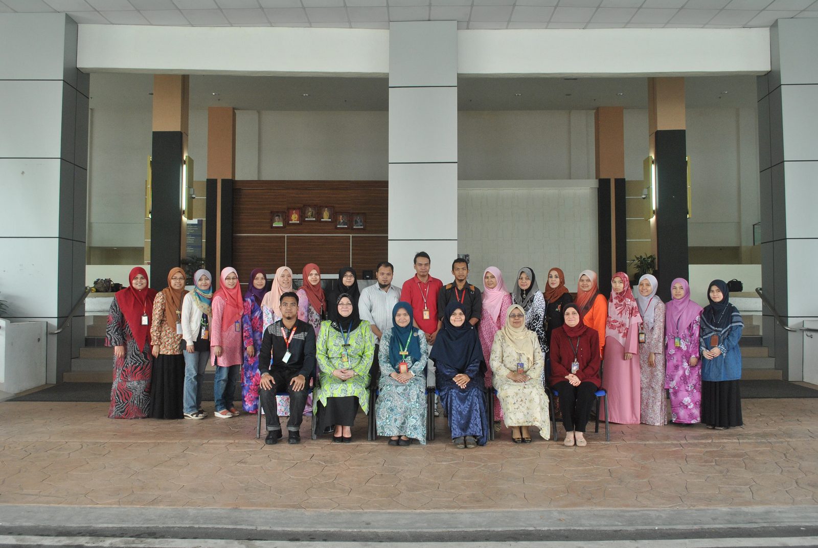 Participants standing and seated in two rows for a group photo in front of a campus building.
