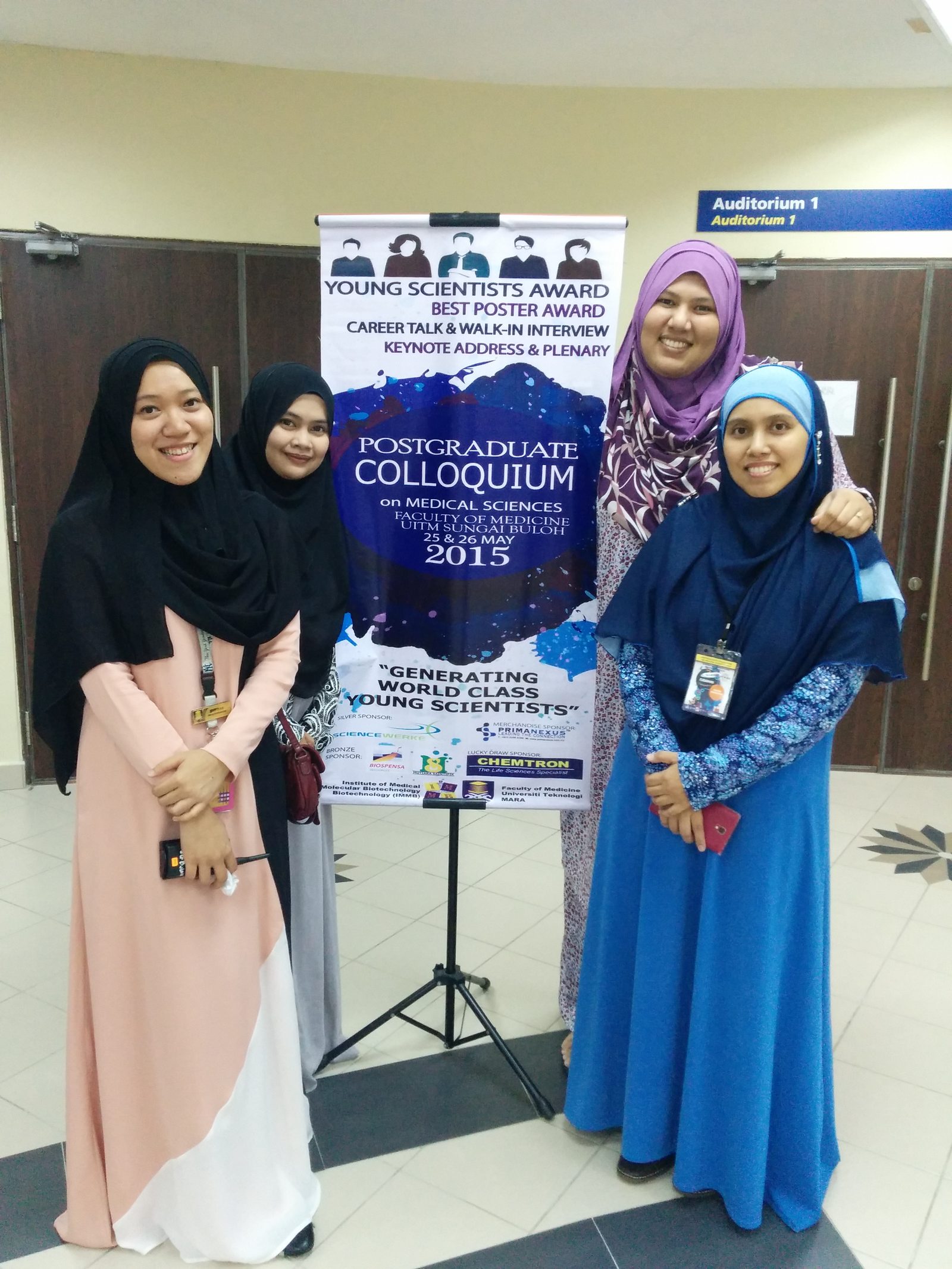 Four participants beside the PCOMS 2015 roll-up banner, which lists Prima Nexus as merchandise sponsor.
