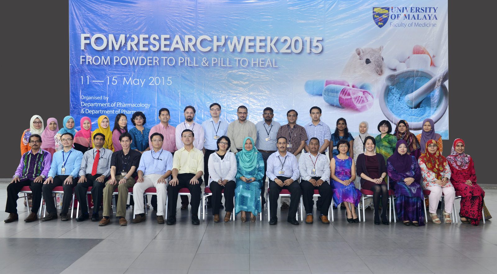 A large group seated and standing in two rows in front of the FOM Research Week 2015 backdrop