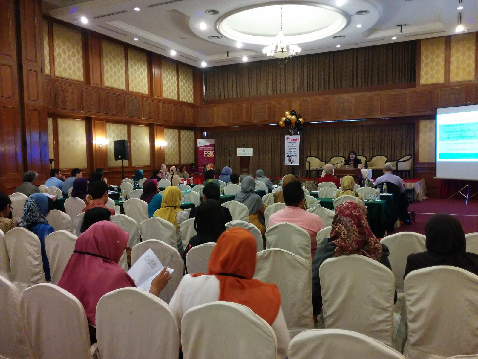 Delegates seated in the main hall facing a speaker at the lectern, with the i-SIHAT 2015 banner and a projector screen