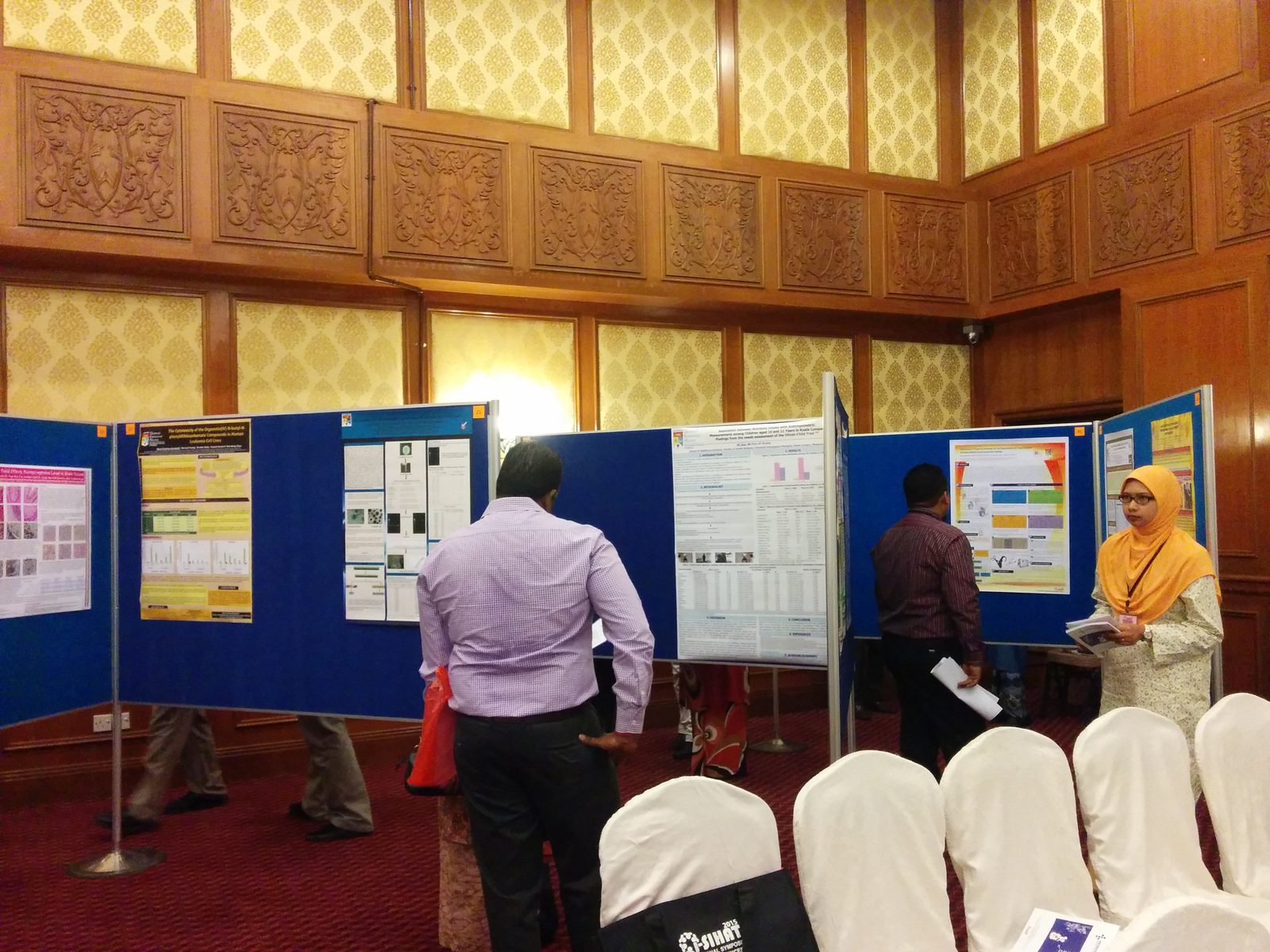 Delegates reading research posters on blue boards in the poster area of the hall
