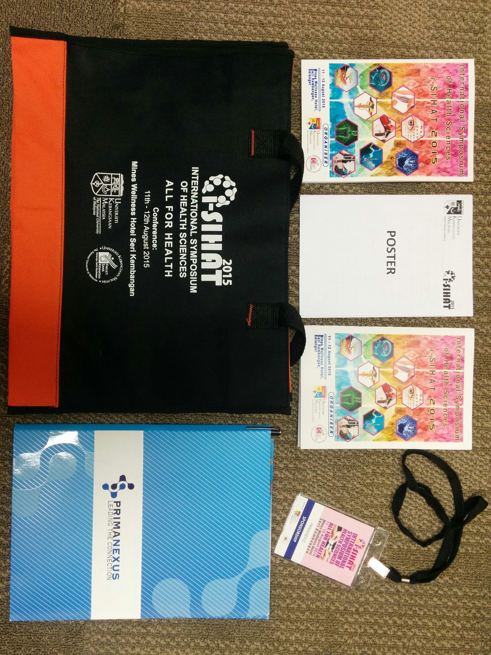 An i-SIHAT 2015 bag, programme books, a poster booklet, a sponsor pass on a lanyard and a Prima Nexus folder on carpet