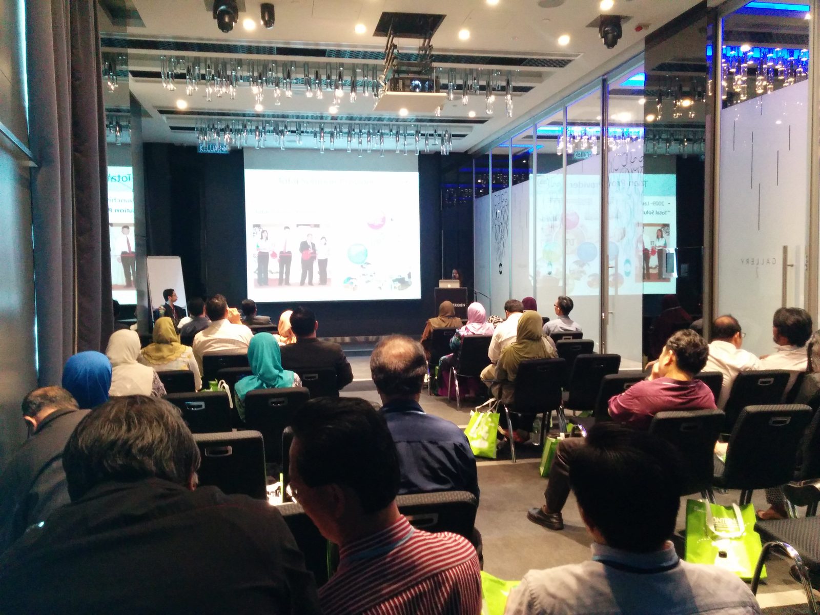 Seated audience in the hotel meeting room watching a talk on the projection screen