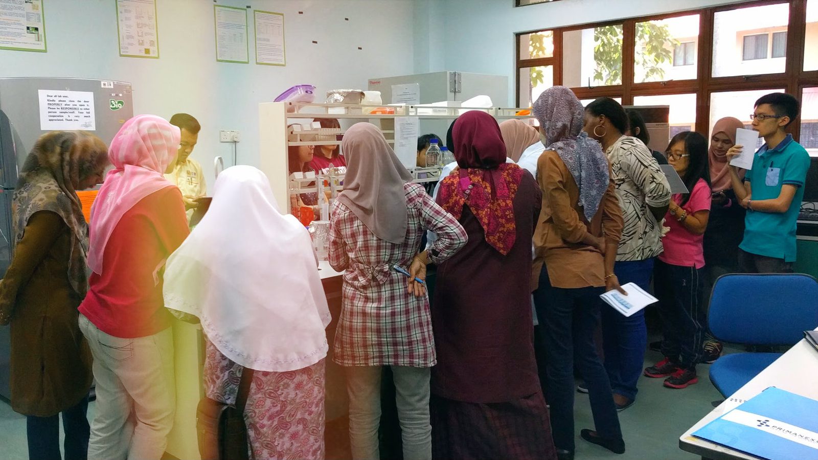 Participants gather around a laboratory bench to watch a step of the ELISA demonstration