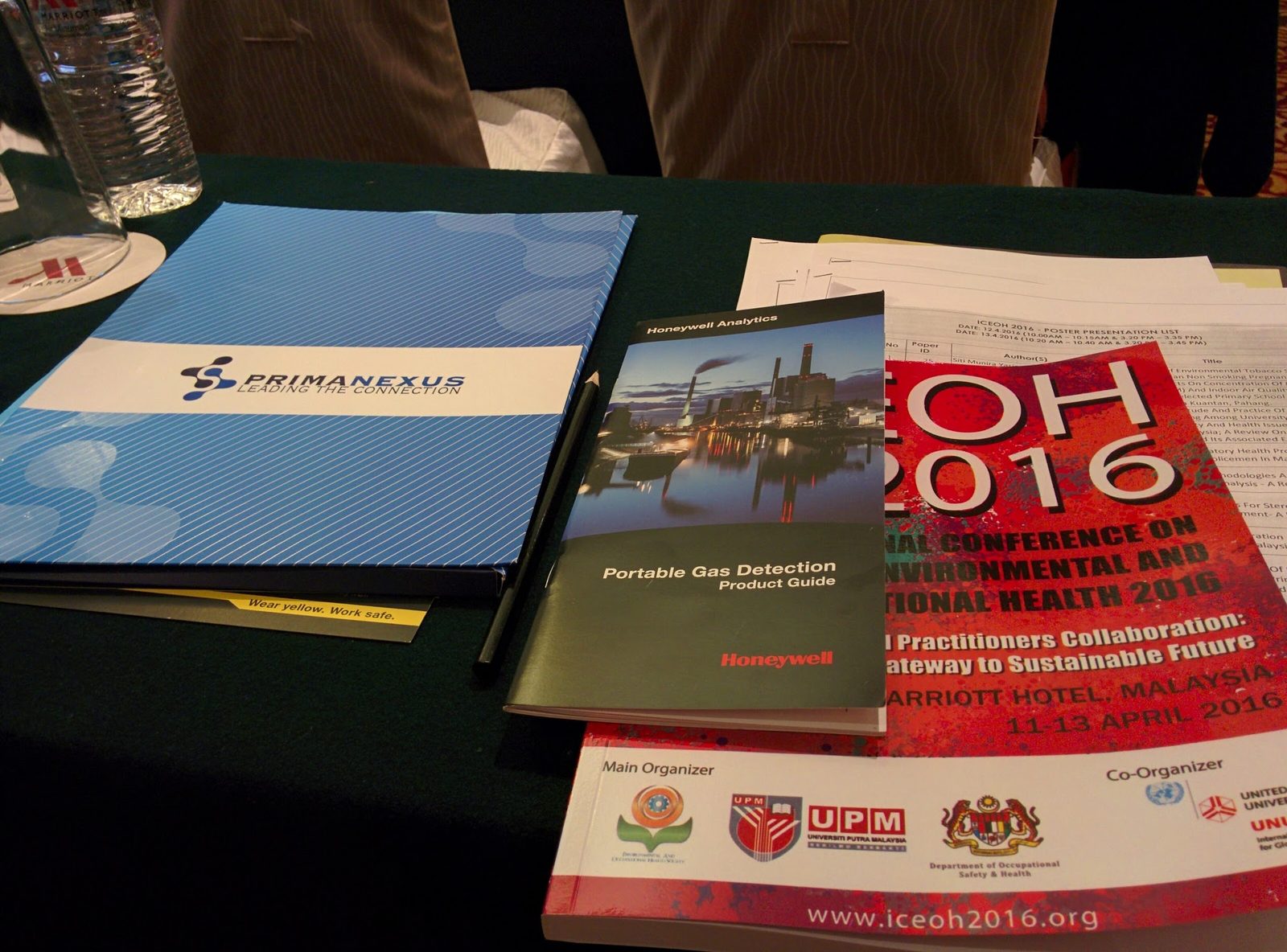 A blue Prima Nexus folder on a conference table beside the red ICEOH 2016 conference book and a brochure