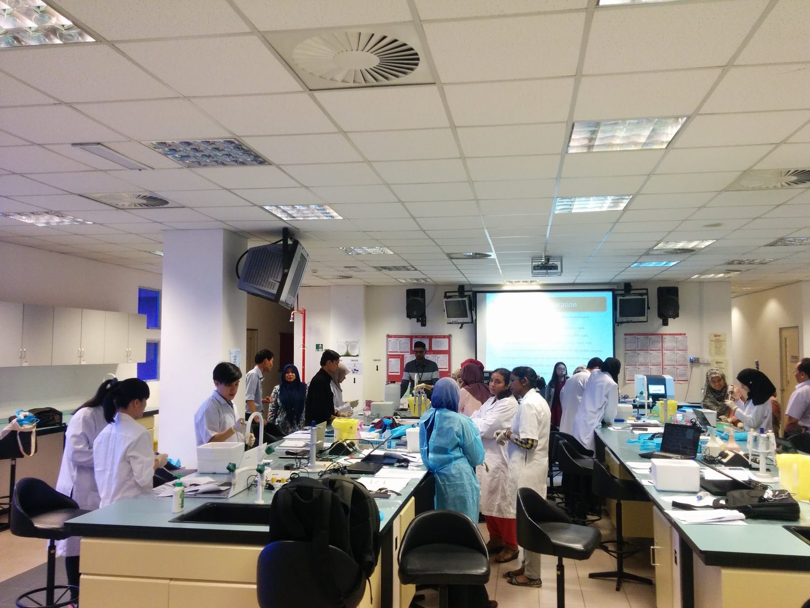 Participants in lab coats working at benches across a large teaching laboratory