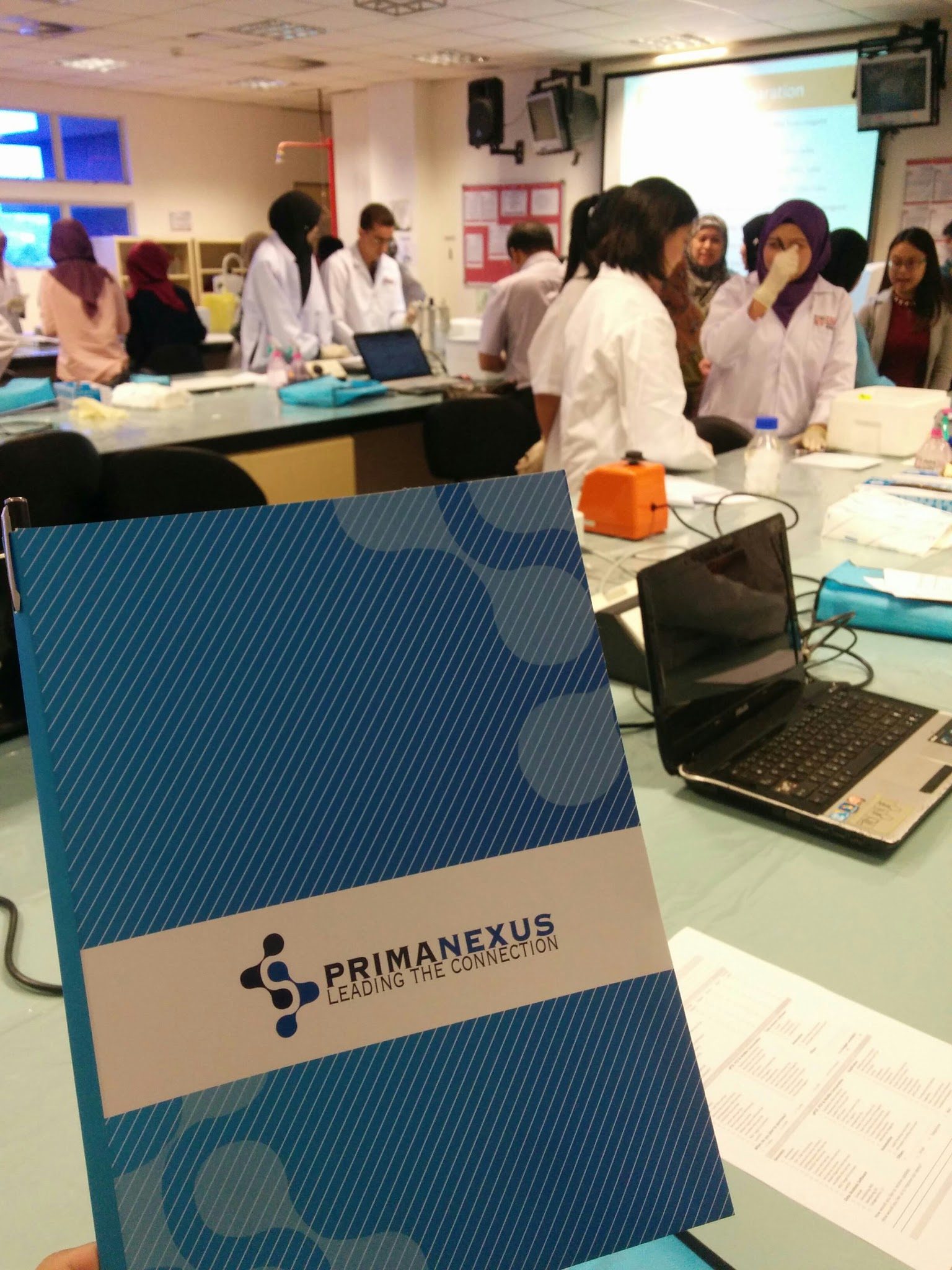 A blue Prima Nexus folder on a laboratory bench, with participants working behind it
