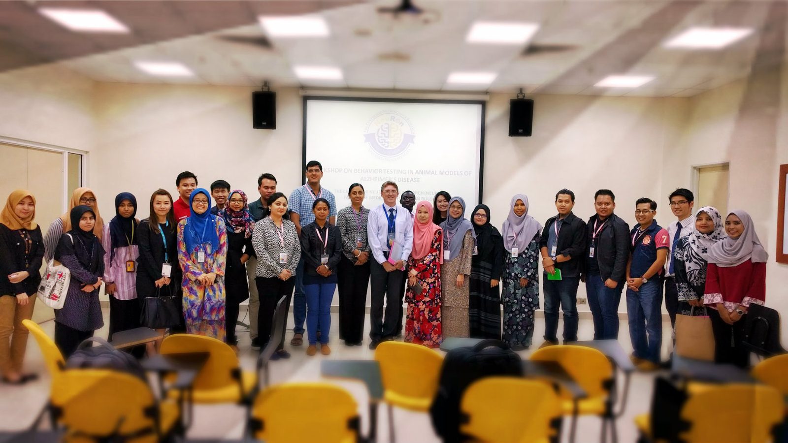 A large group of participants and organisers standing together for a group photo in a seminar room