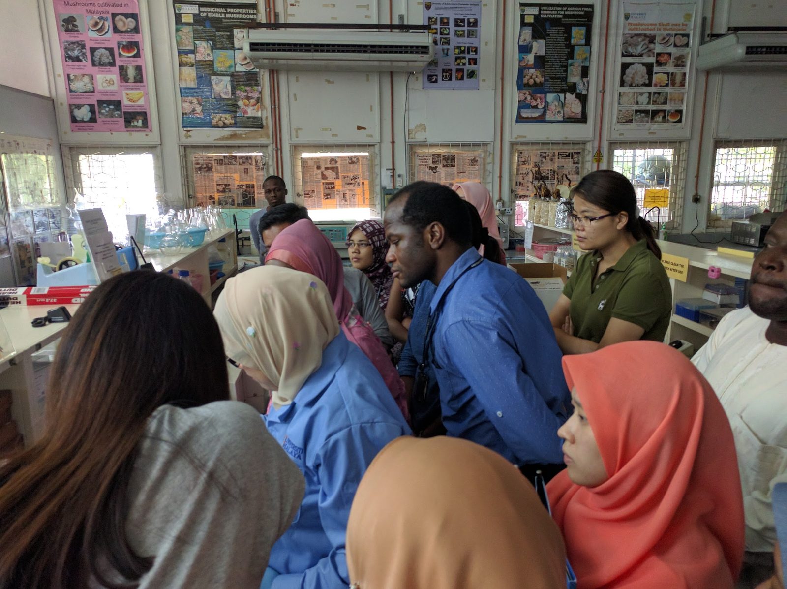 Participants crowd around a lab bench to watch a step of the ELISA demonstration.