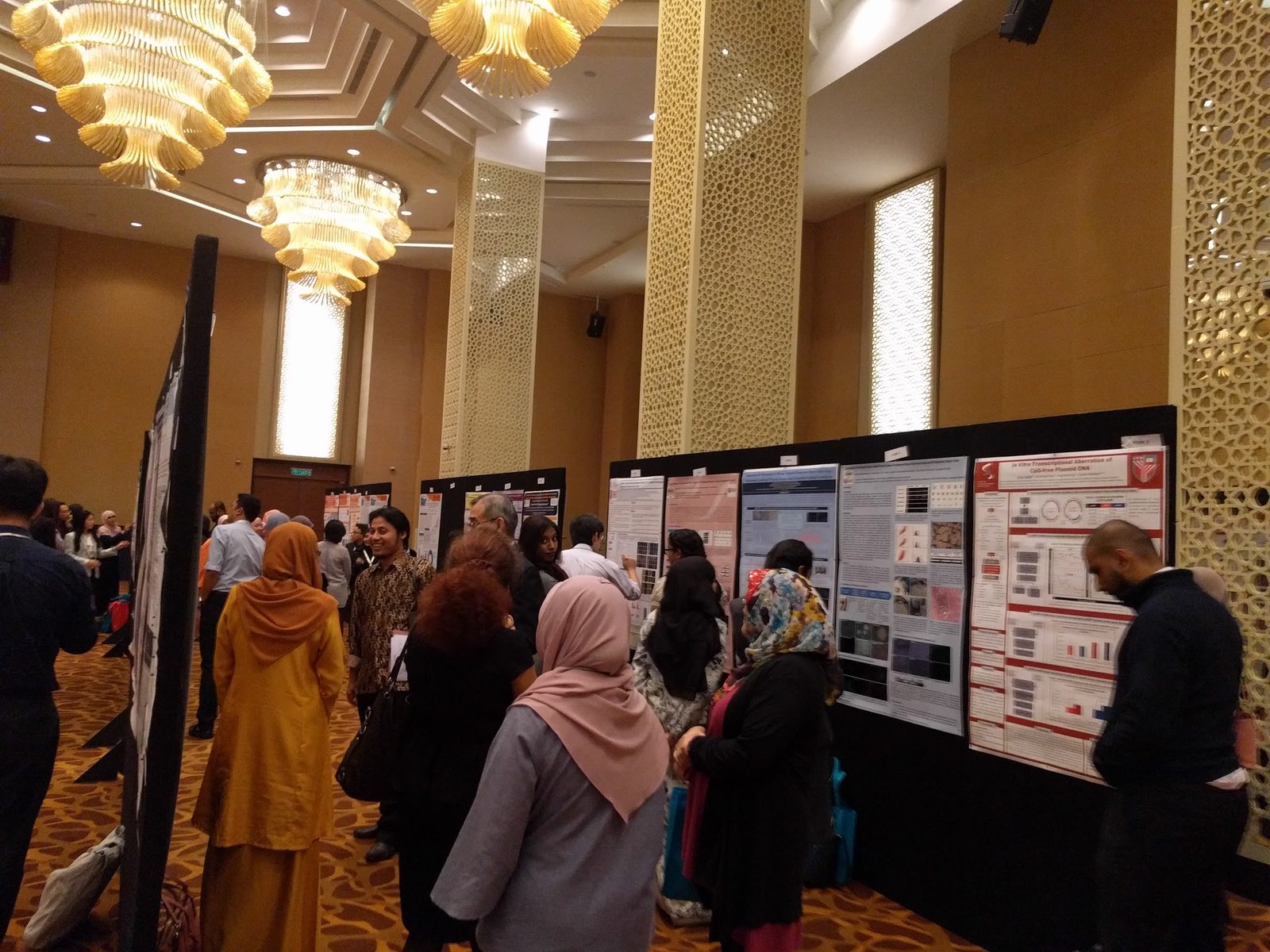 Delegates standing and reading research posters along a row of boards in the hotel hall
