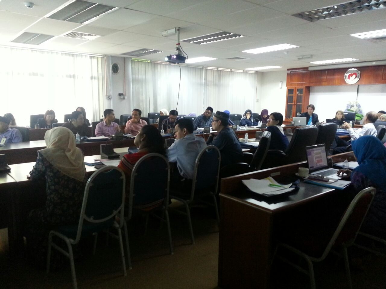 Workshop participants seated at desks in a large meeting room at the Institute for Medical Research