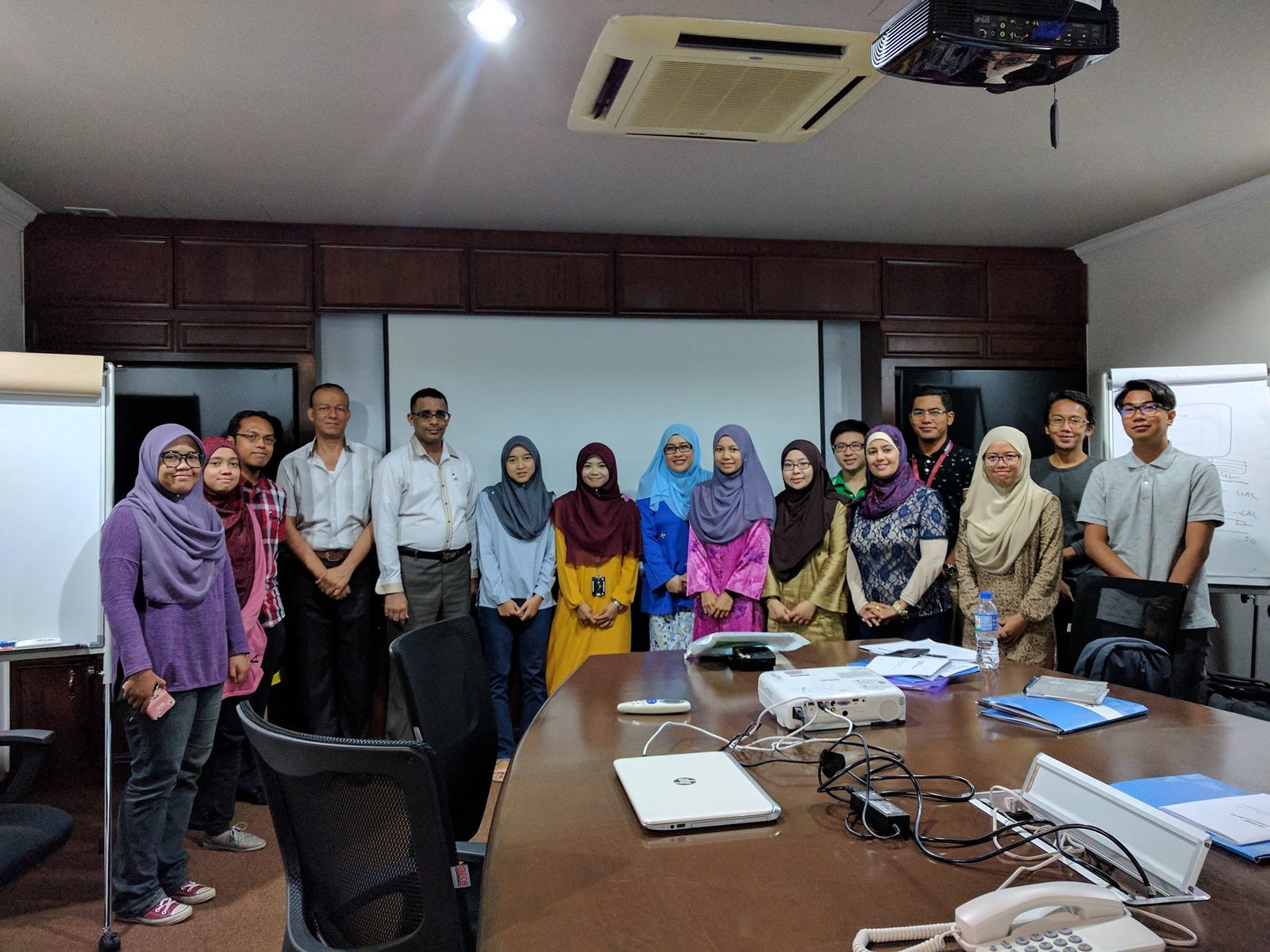 The workshop group standing together for a photo in a meeting room with a long table and a projector