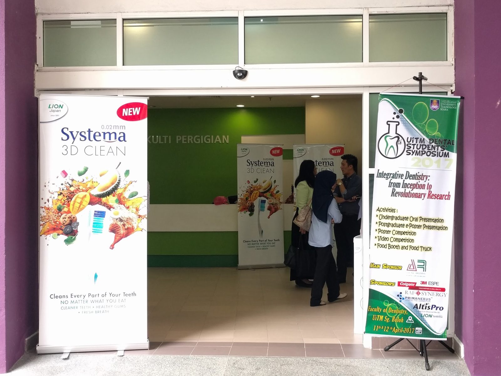 The Faculty of Dentistry entrance, with visitors inside and the symposium banner on a stand by the door