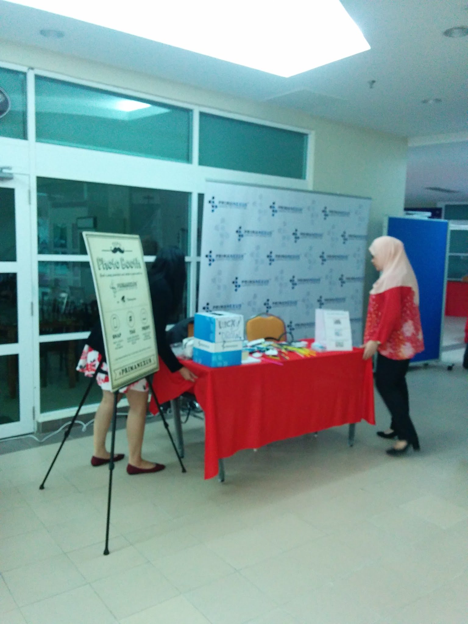 The Prima Nexus photo booth: a branded backdrop, a table of props and a Photo Booth sign on an easel