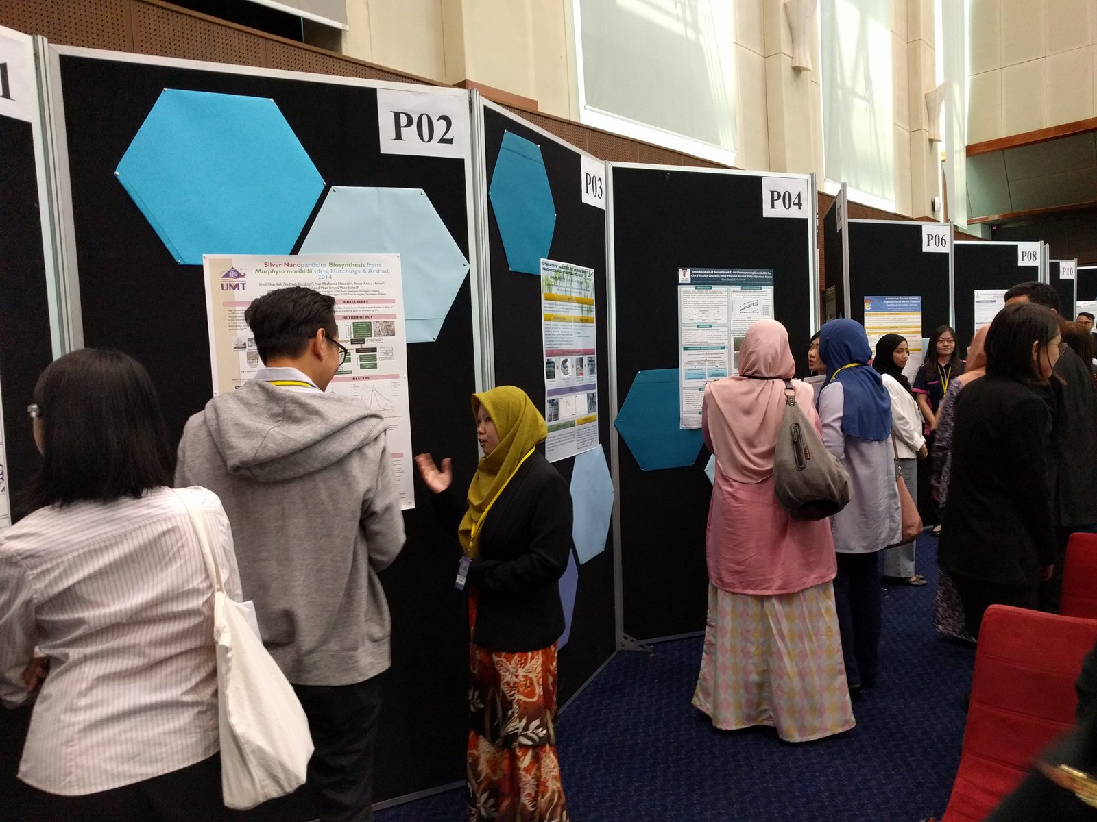 Visitors read research posters pinned to numbered display boards in the ballroom