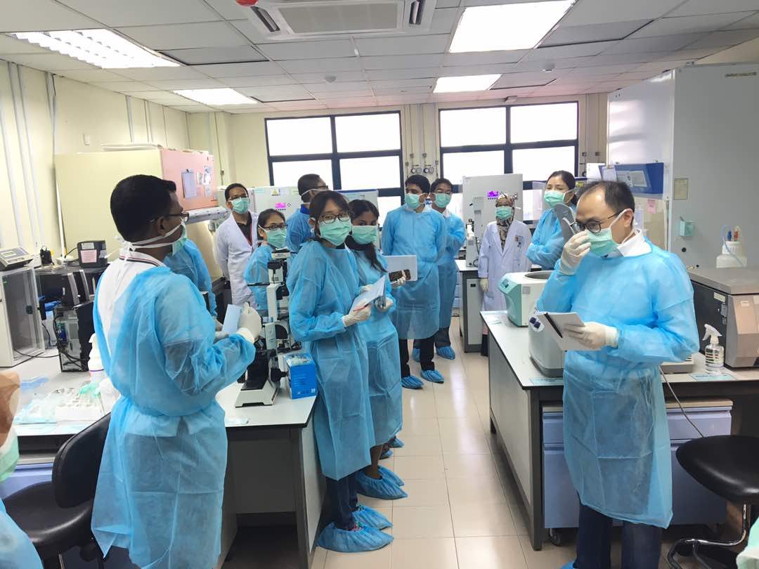 Workshop participants in blue gowns, masks and shoe covers in the tissue culture laboratory
