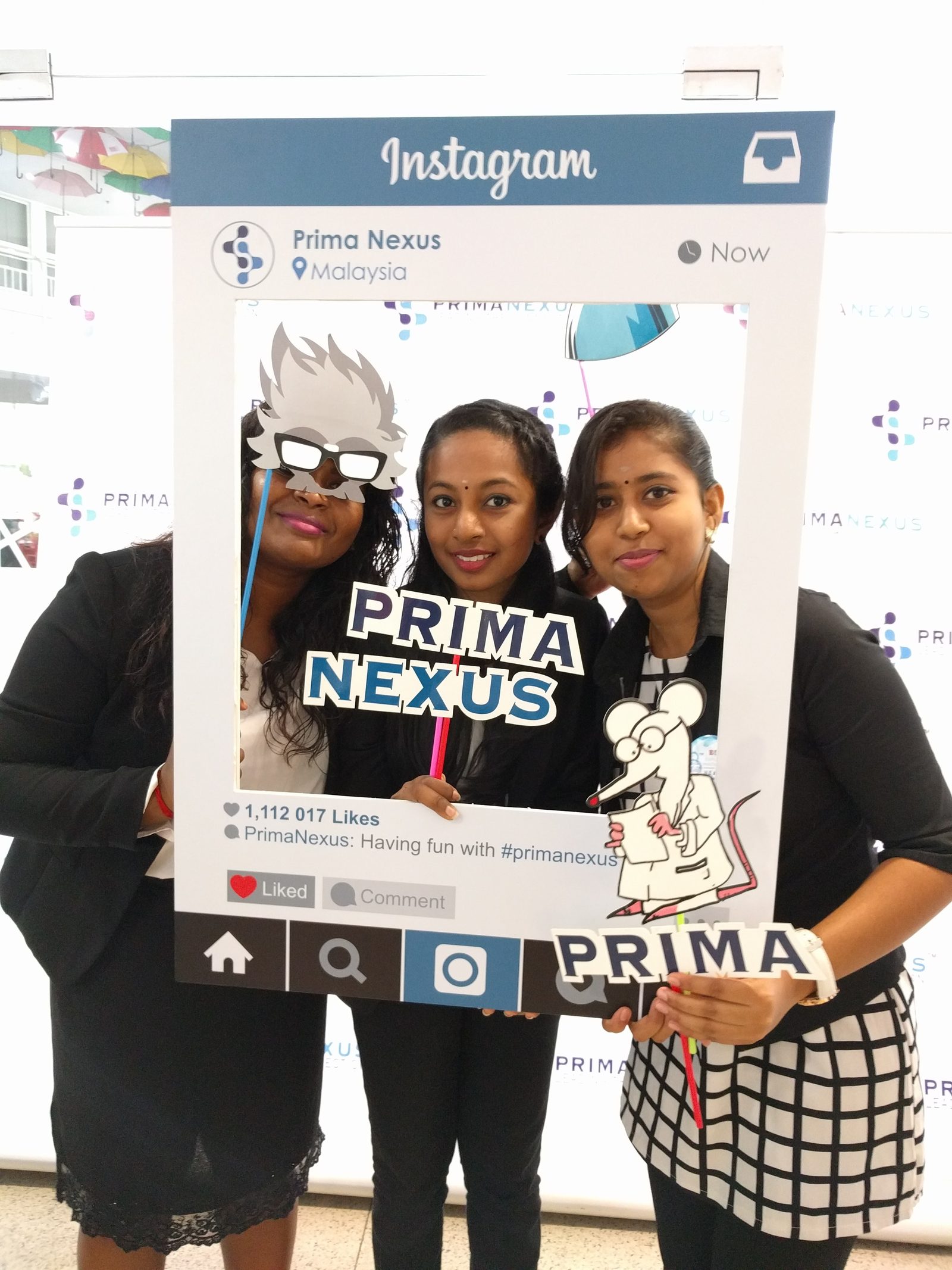 Three participants holding Prima Nexus props inside a large social media style photo frame