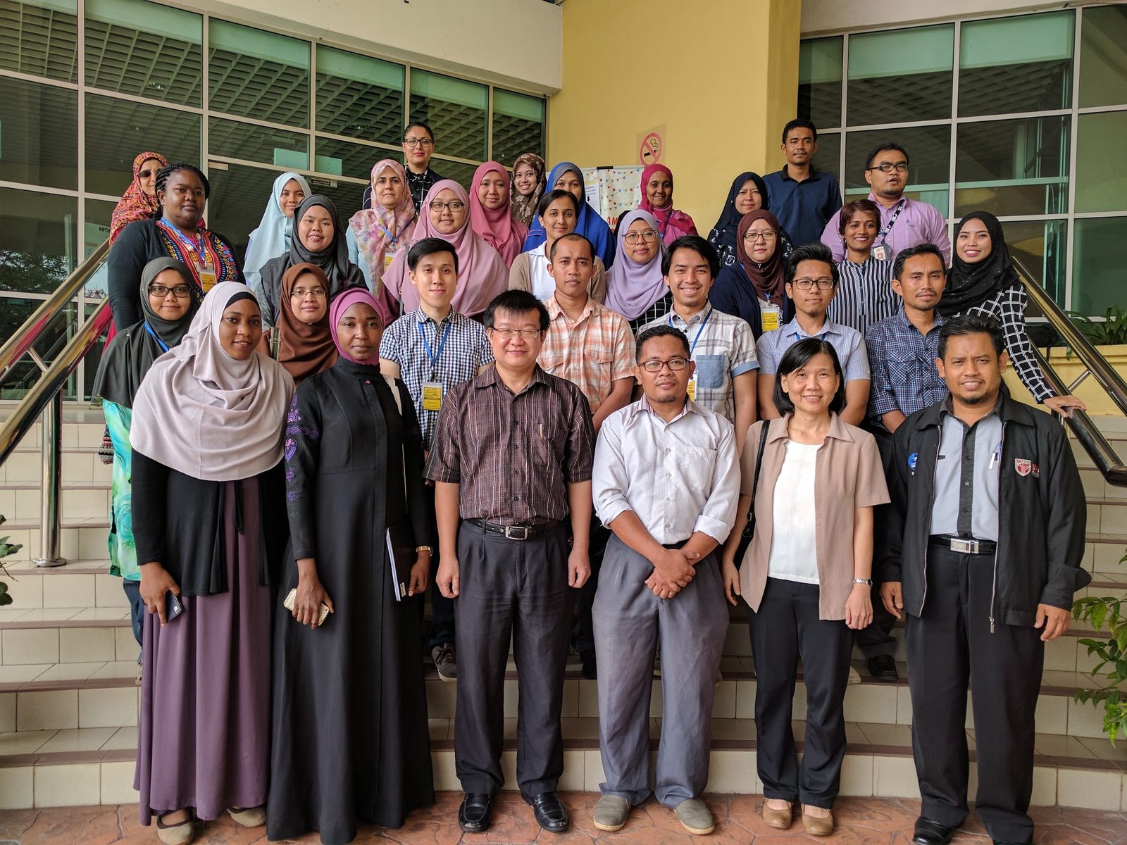 Workshop participants gathered for a group photo on an outdoor staircase at UPM