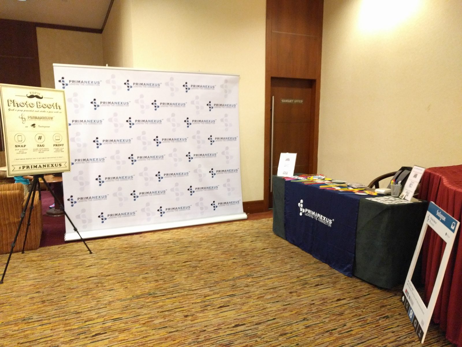 Prima Nexus stand with a branded backdrop, a photo booth sign and a table with a Prima Nexus cloth