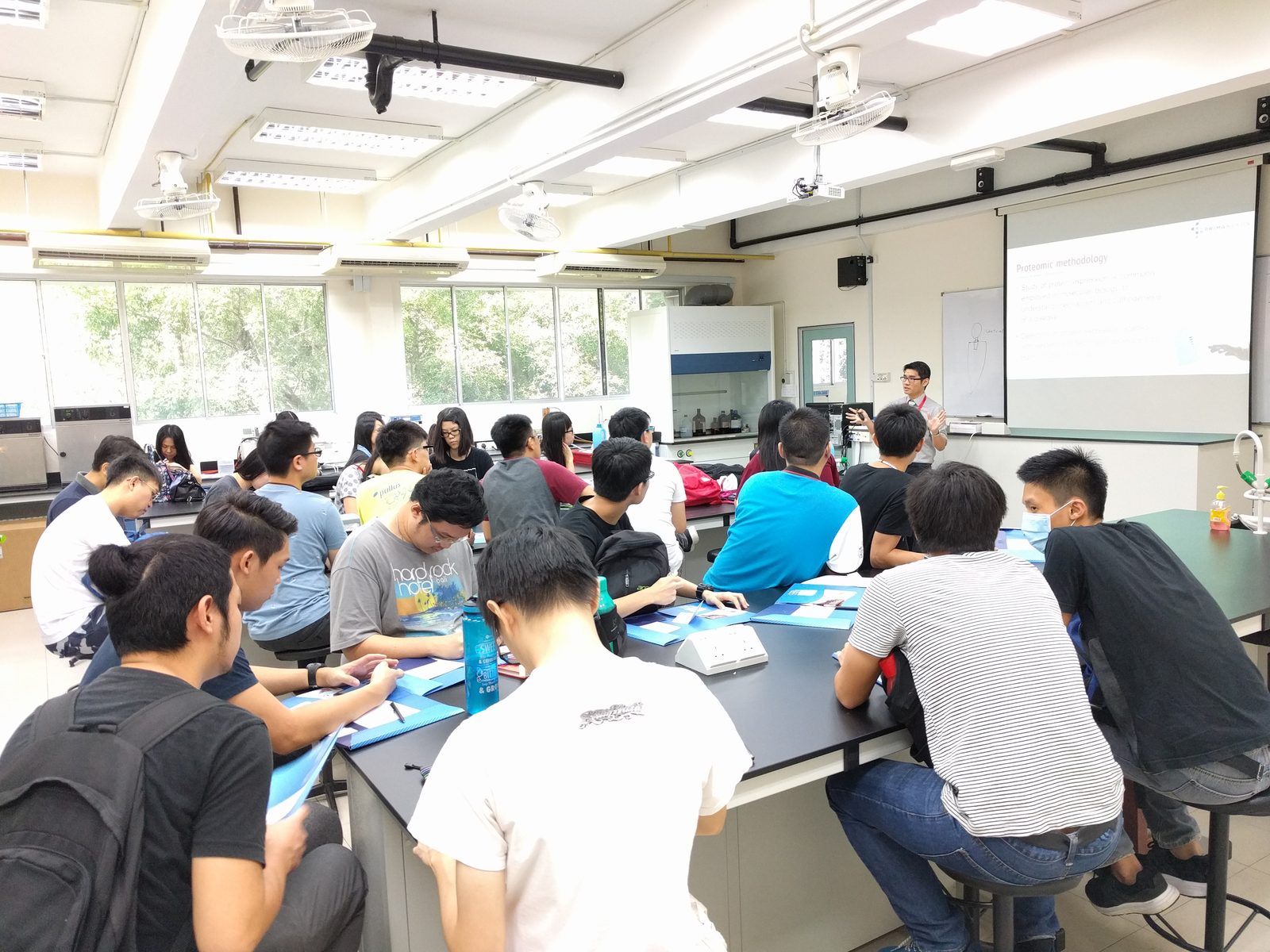 Participants with notes at laboratory benches while the speaker talks at the front of the room