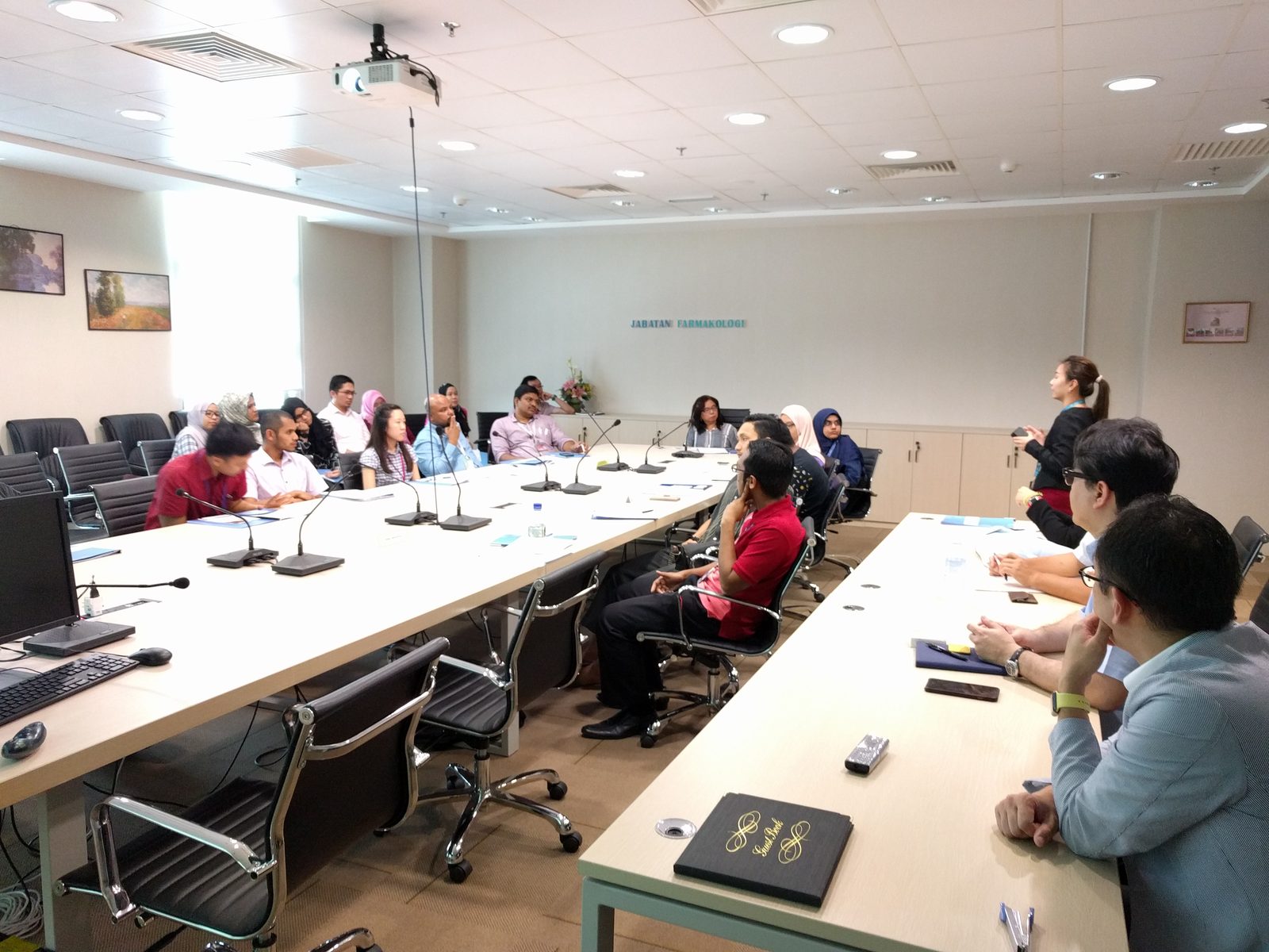 Researchers seated around long tables in the PPUKM seminar room, with a presenter standing at the front