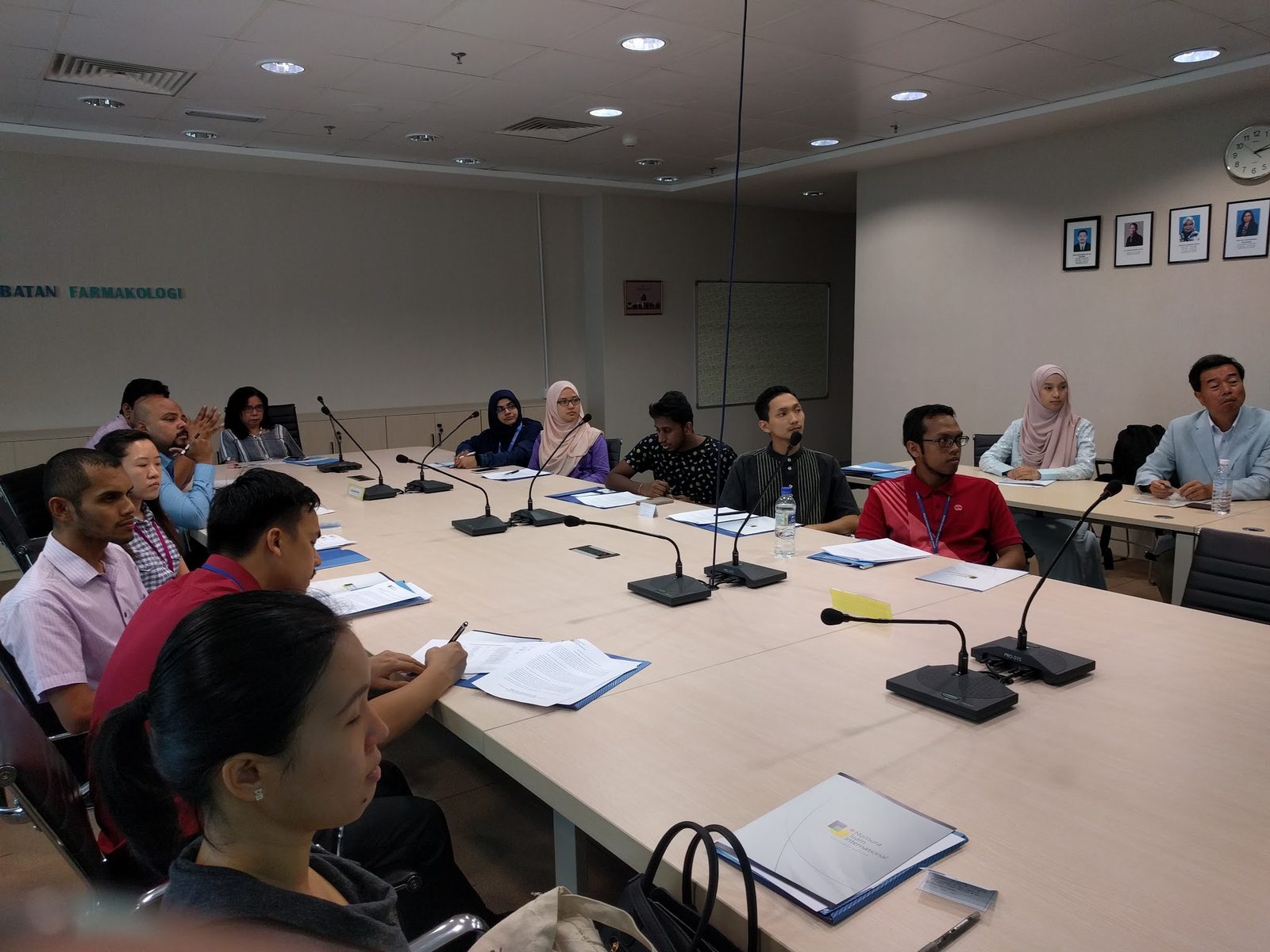 Participants seated along the conference table during the seminar, one taking notes