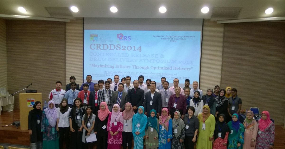 Delegates of CRDDS2014 pose for a group photo in a lecture hall, in front of the symposium title slide