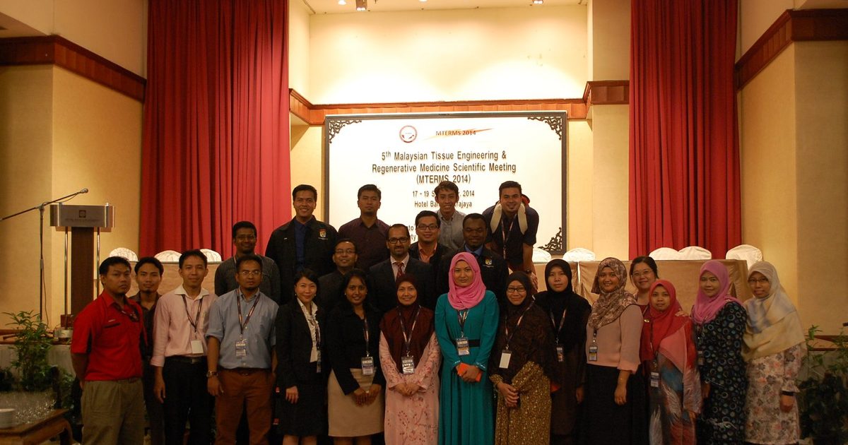 Delegates of MTERMS 2014 pose for a group photo in a hotel hall, in front of a board with the meeting name, dates and venue