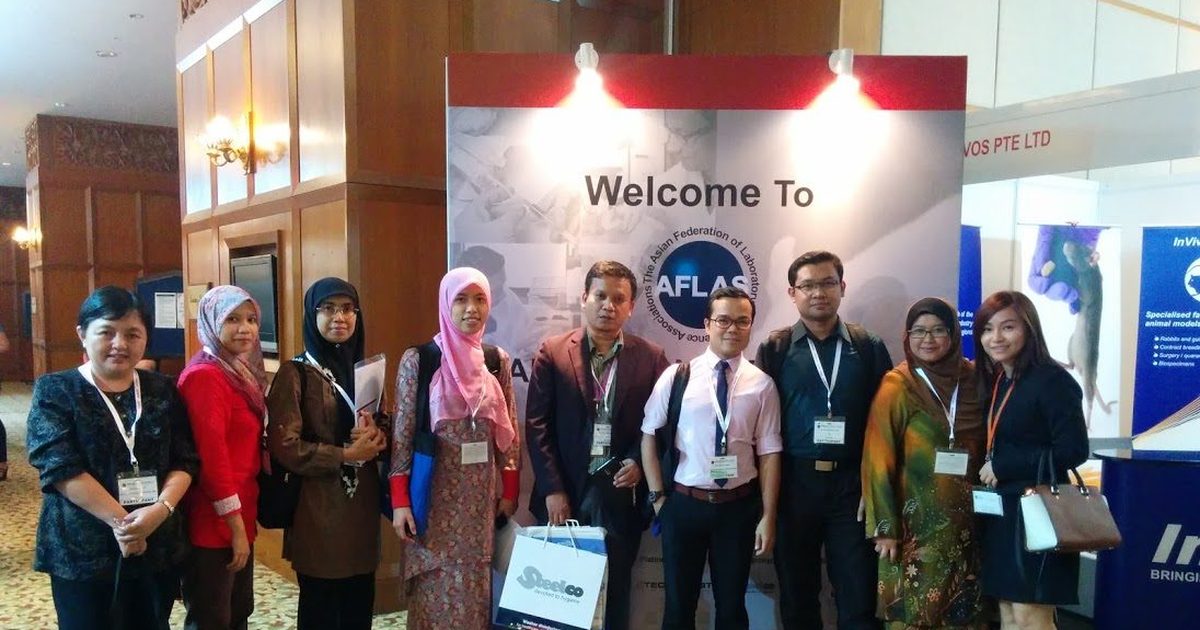 Nine delegates stand together in front of the Welcome to AFLAS board at the congress