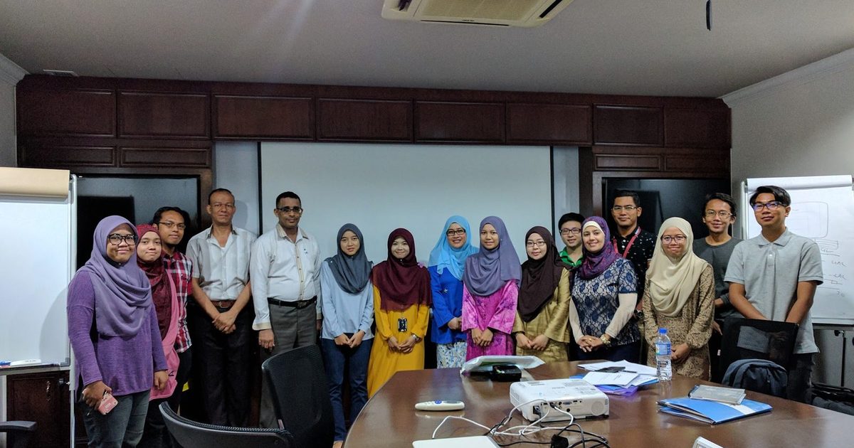 The workshop group standing together for a photo in a meeting room with a long table and a projector