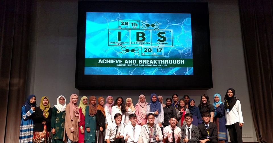 Participants pose for a group photo on stage under a large screen showing the IBS 2017 seminar logo