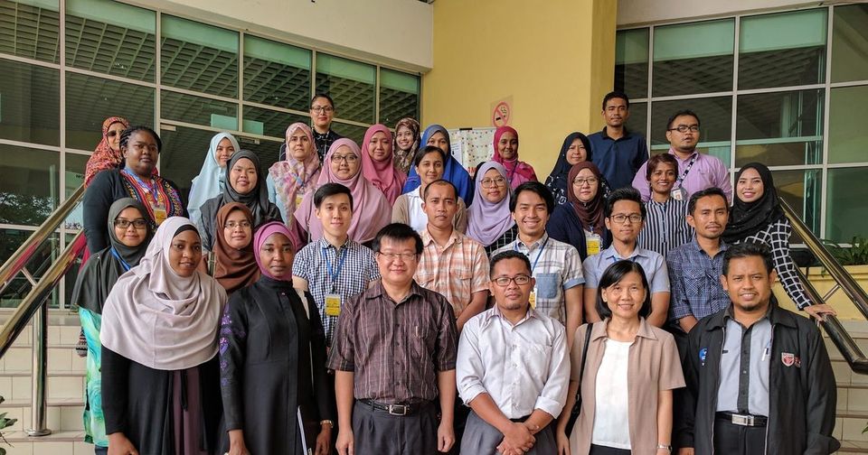 Workshop participants gathered for a group photo on an outdoor staircase at UPM