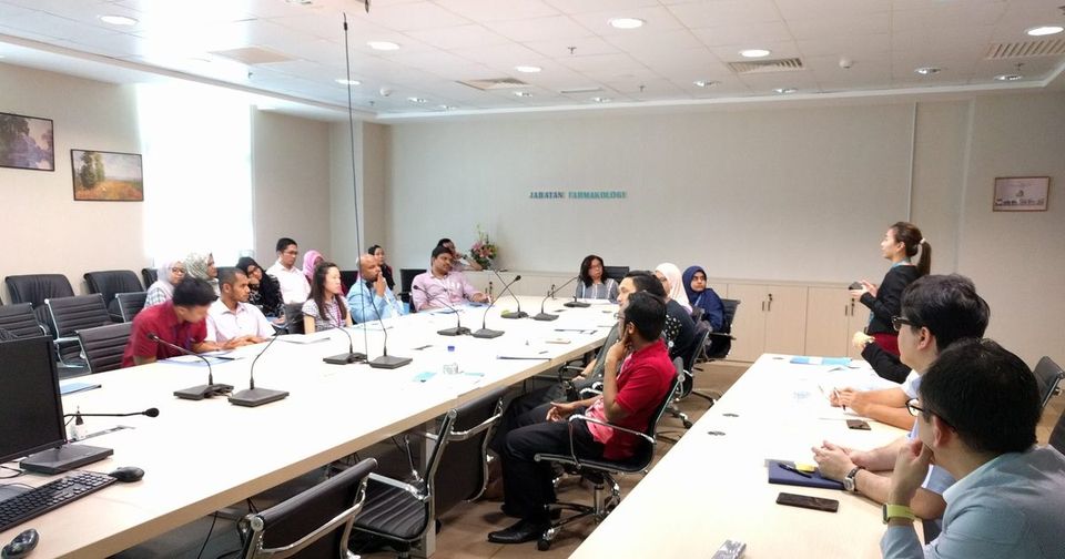 Researchers seated around long tables in the PPUKM seminar room, with a presenter standing at the front