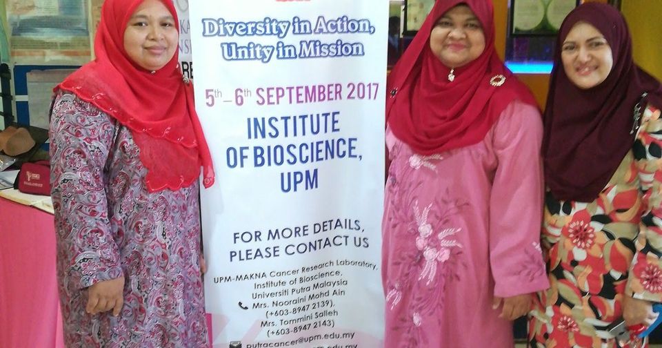 Three delegates stand beside the Putra Cancer Research Symposium 2017 banner at the Institute of Bioscience, UPM