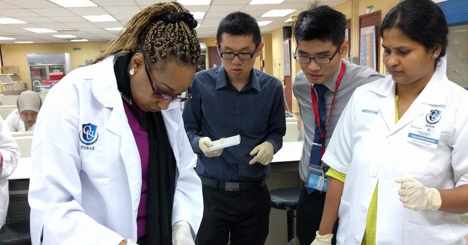 A trainer demonstrates a step at the laboratory bench while participants watch