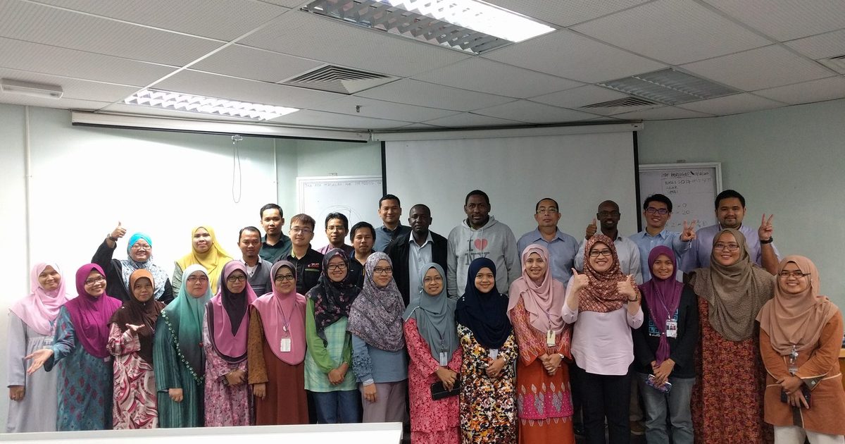 Group photo of the workshop participants standing in rows in front of the screen in a lecture room