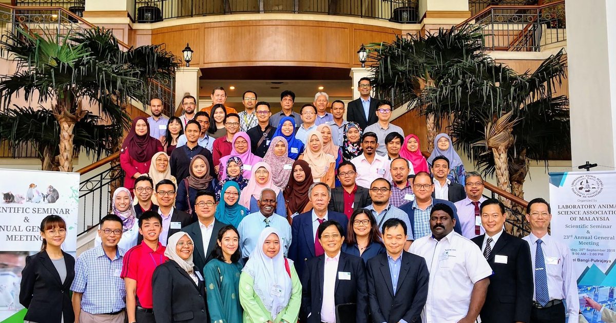 Large group photo of LASAM members and guests on a hotel staircase, between two LASAM banners