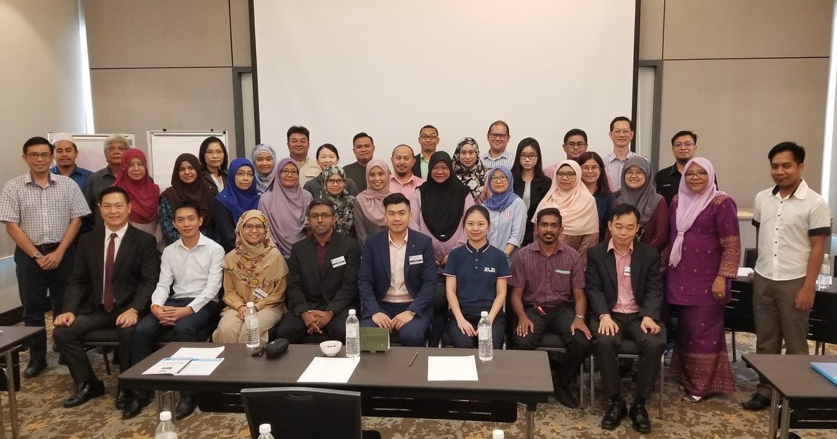 Group photo of LASAM members and speakers, standing and seated, at the front of a hotel meeting room
