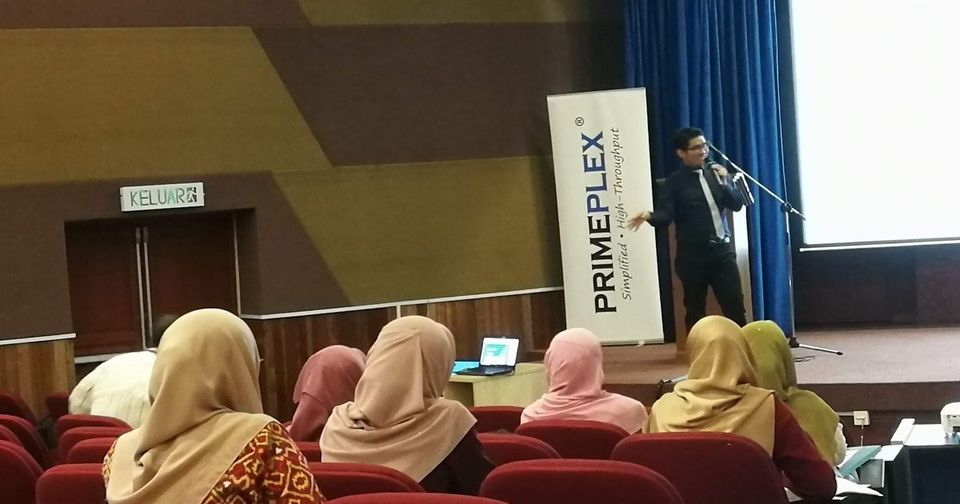 A Prima Nexus representative speaks from the stage of a lecture hall at IIUM Kuantan, with participants seated in the foreground