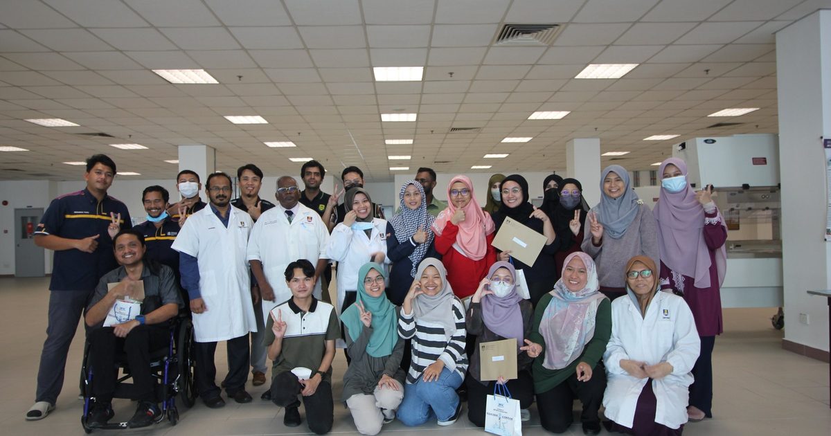 Workshop participants, trainers and staff, some in lab coats, in a group photo in a large laboratory hall