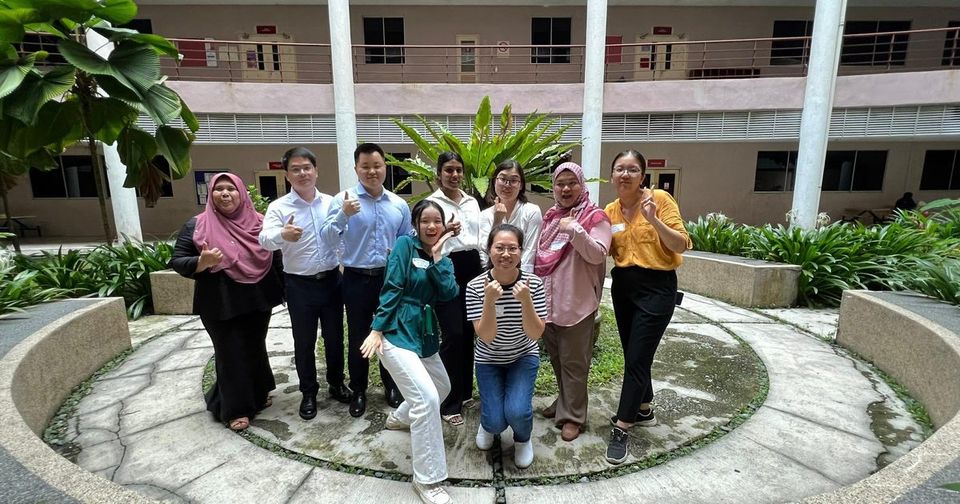 Workshop participants and trainers in a group photo in a courtyard with a round planter