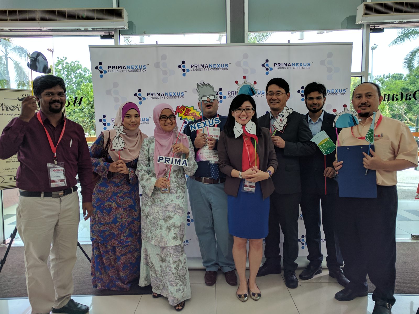 Delegates holding science-themed props in front of the Prima Nexus backdrop at IABS2017