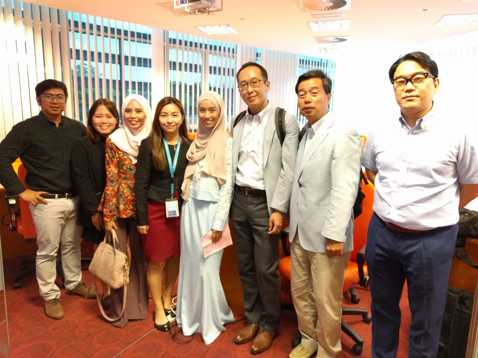 Eight people stand in a row for a group photo in the seminar room at UPM at the end of the seminar.