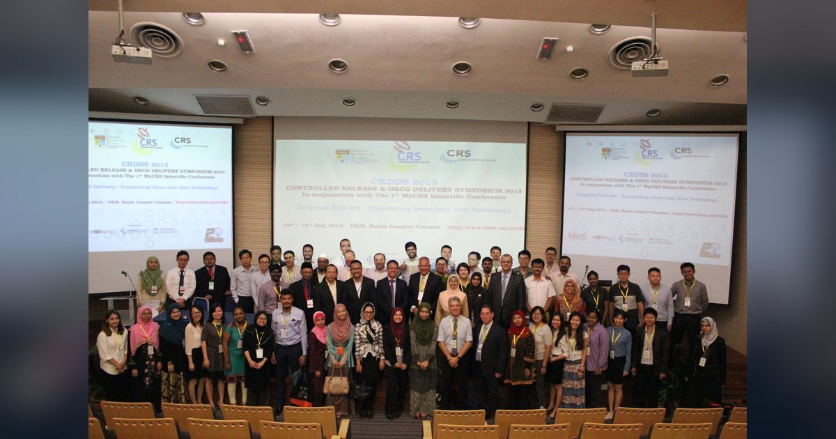 Delegates of CRDDS2015 pose for a group photo in a lecture hall, with the symposium title on three screens