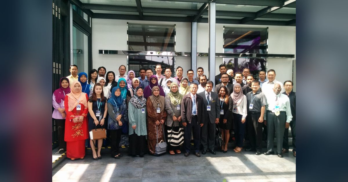Group photo of the seminar participants standing in rows under a glass canopy at Le Meridien Kuala Lumpur