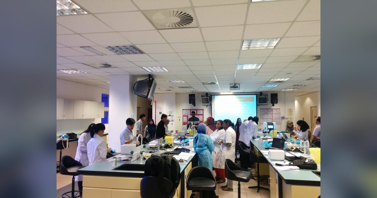 Participants in lab coats working at benches across a large teaching laboratory